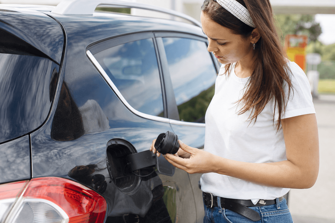 Personne vérifiant le bouchon du réservoir de carburant d'une voiture, trappe à carburant ouverte